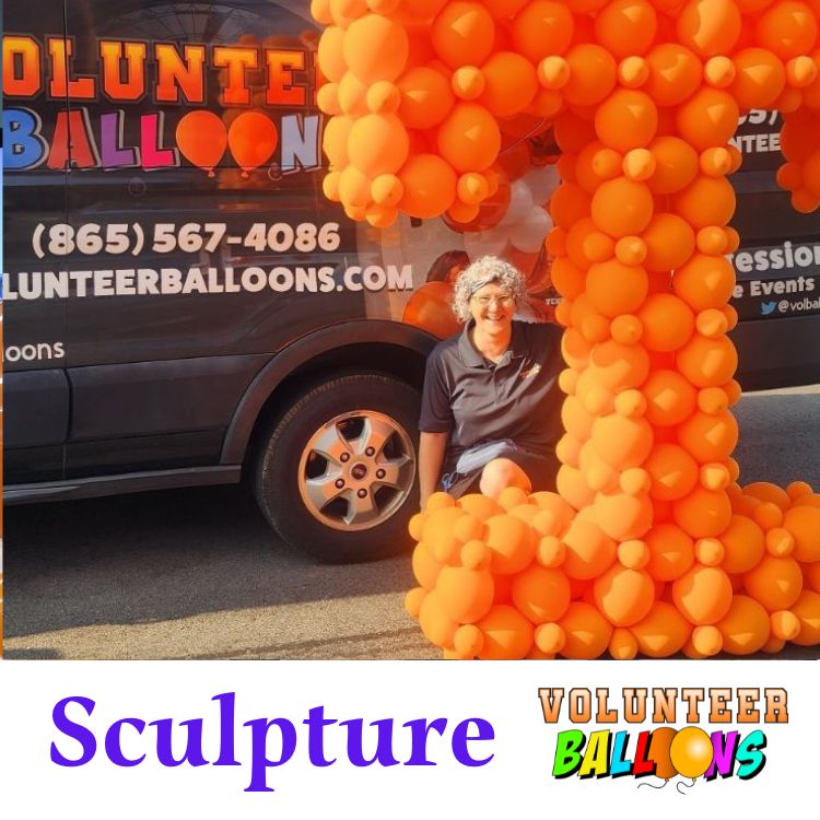 balloon sculpture of an orange Power T with the owner of Volunteer Balloons kneeling behind it, and the background is the Volunteer Balloons delivery van