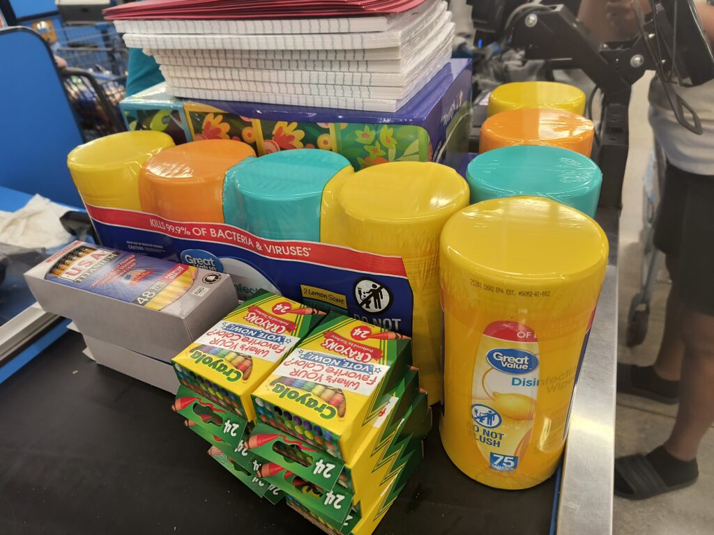 Various school supplies like crayons and filler paper and sanitizing wipes at the checkout register