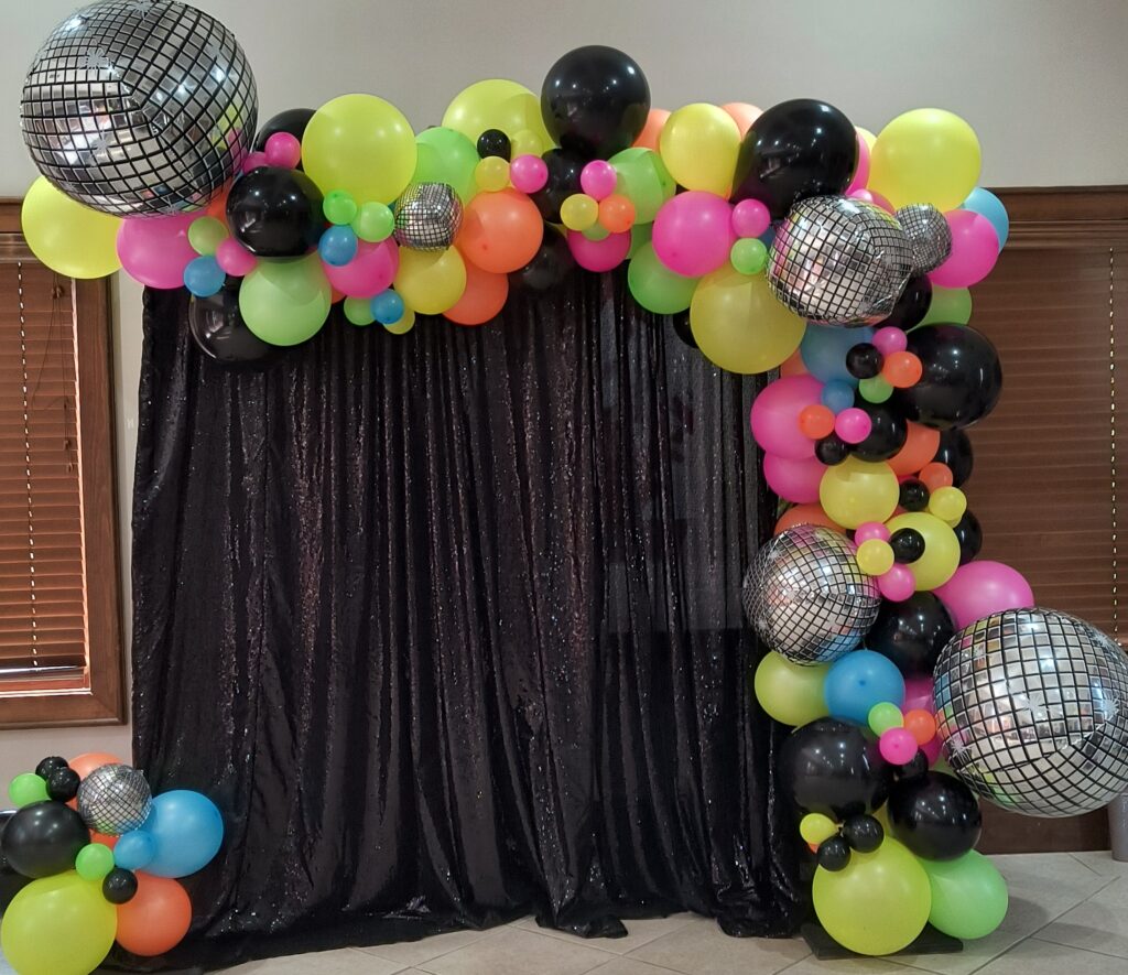 Balloon garland with neon balloon around a black backdrop