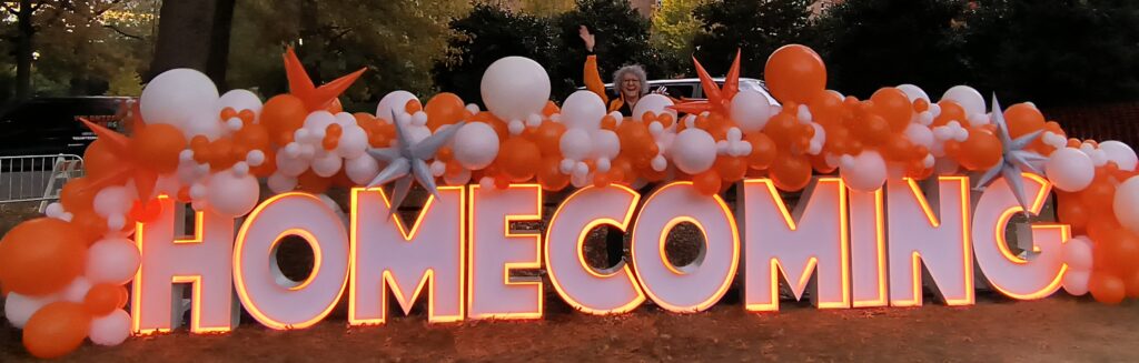 Large illuminated HOME COMING marquee letters with orange and white balloon garland for a school homecoming event in Knoxville Tennessee.