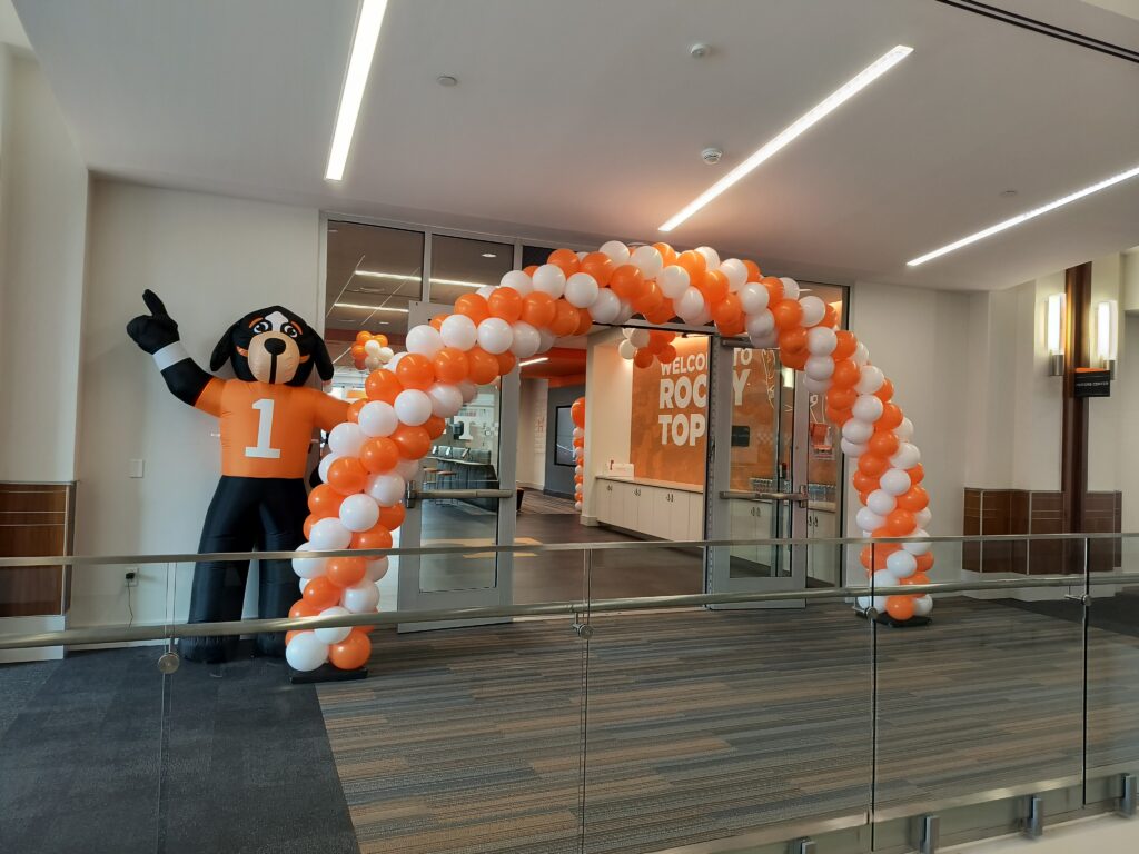 Official orange and white balloon arch by Volunteer Balloons at the UT Visitor Center with Smokey the mascot.