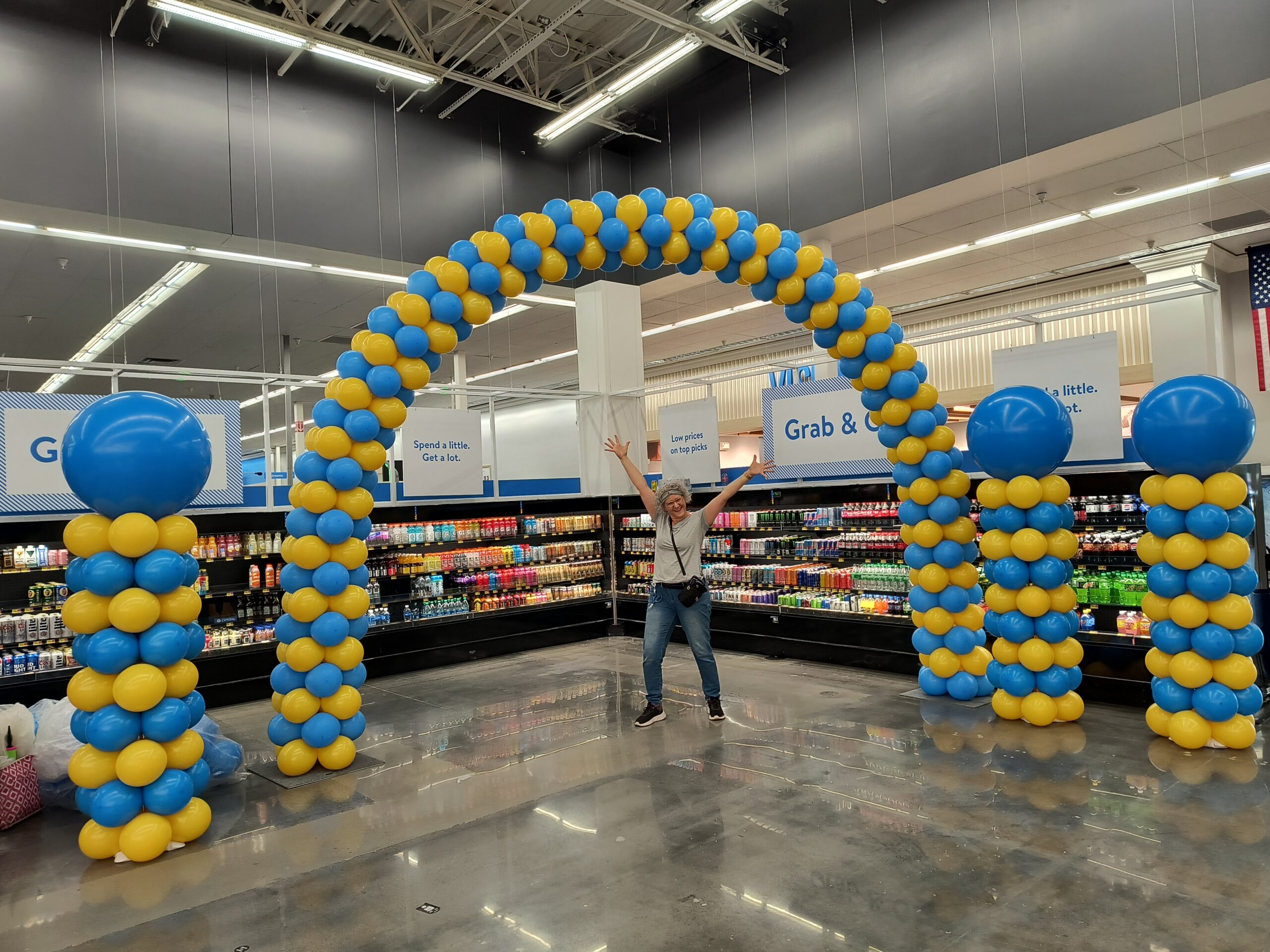 Large balloon arch in Walmart Knoxville with matching balloon columns and the owner of volunteer balloons standing below the arch for size comparison